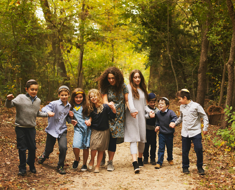 family and newborn photographer, extended family picture, group of nine children holding hands, boys and girls walking through the forest