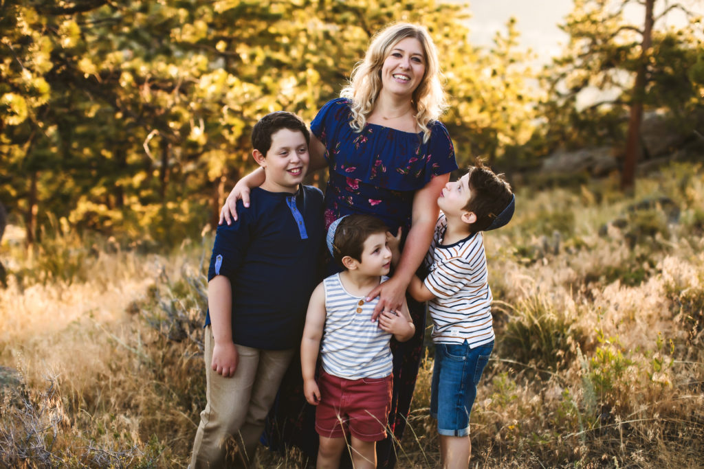 Family Photographer, Chana Grossman, Stands with her three boys outside in the forest